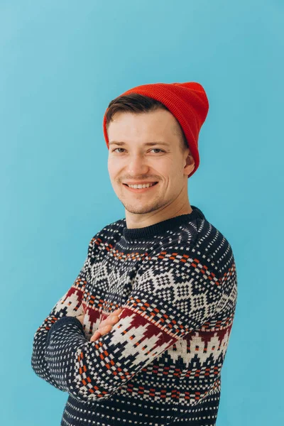 迷人的男人身穿圣诞毛衣 头戴深蓝色背景的红帽子的照片 — 图库照片