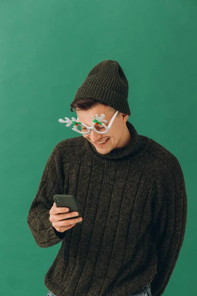 Een Jonge Man Een Warme Trui Een Carnavalsbril Een Telefoon — Stockfoto