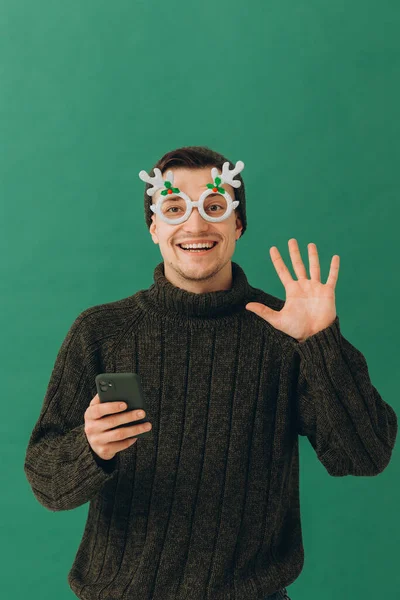 Ein Junger Mann Warmem Pullover Karnevalsbrille Und Handy Der Hand — Stockfoto