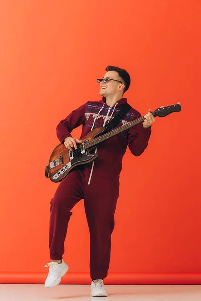 クリスマス キグルミの若い男がカラーを背景にエレキギターを弾く — ストック写真