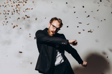 Kutlama zamanı. Parlak konfeti altında dans eden mutlu bir adamın portresi..