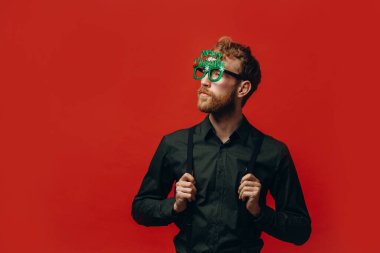 Yeni yıl partisinde karnaval gözlüklü kızıl saçlı yakışıklı adam. Stüdyo fotoğrafı.