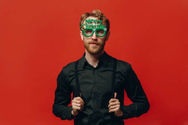 Yeni yıl partisinde karnaval gözlüklü kızıl saçlı yakışıklı adam. Stüdyo fotoğrafı.