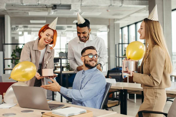 Surprise. Mixed race happy people celebrating a birthday of colleague in the modern offic