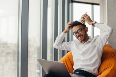 Doğum gününü kutladıktan sonra ofiste dizüstü bilgisayarla çalışan genç bir Hindu. Ofiste doğum günü kutlaması.