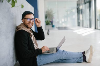 Urgent task. A man is sitting on the floor with a laptop.