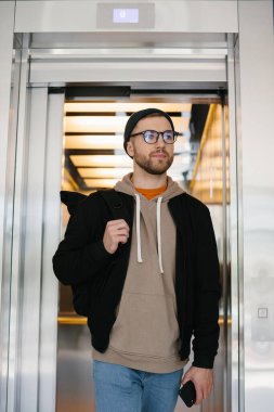 A young man uses an elevator. IT specialist on the background of an elevator in an office building.