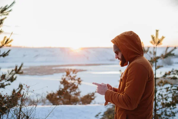 一位徒步旅行者在冬日的群山中欣赏日落 并在手机上拍照 — 图库照片