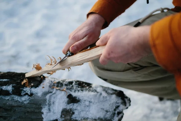 Mężczyzna Przygotowuje Wełnę Drzewną Nożem Wzniecenia Pożaru Zimowym Lesie Zachodzie — Zdjęcie stockowe