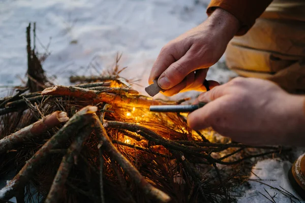 Closeup of male hand starts fire with magnesium fire steel, fire striker. Survival concept
