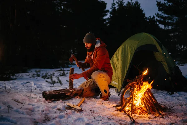 一个游客在夜里在森林里砍柴生篝火 — 图库照片