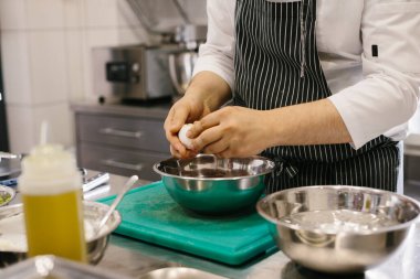 Kapatın. Erkek bir aşçı bir restoranın mutfağında haşlanmış yumurta temizliyor..