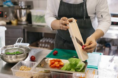 Lezzetli bir kase yemeği için sebze hazırlıyorum: Çağdaş bir restoranın mutfağında bir erkek şef..