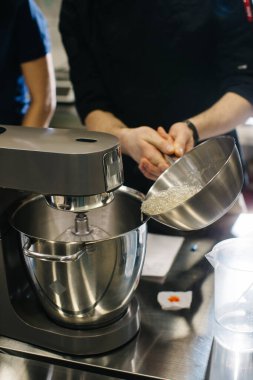 Şef hamur karıştırıcıyla çalışıyor. Karamel ekleniyor, yakın plan.