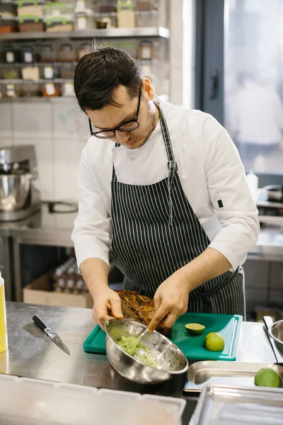 シェフは料理を準備している 広々としたモダンなキッチンでアボカドトーストを準備する男性シェフのクローズアップ — ストック写真