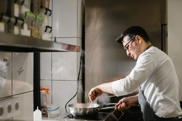 人々のコンセプト レストランキッチンでフライパンで調理する男性シェフ — ストック写真
