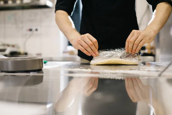 Close up. The cook wraps the dough in cling film, making macaroons or cakes.