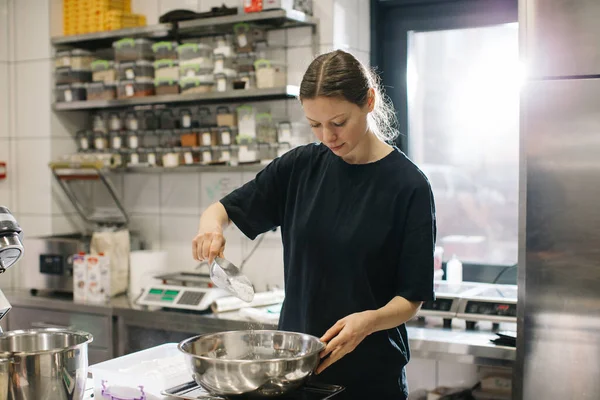 女性の料理人は現代の工業用キッチンで働いています パン屋やカフェでケーキを作る過程 — ストック写真