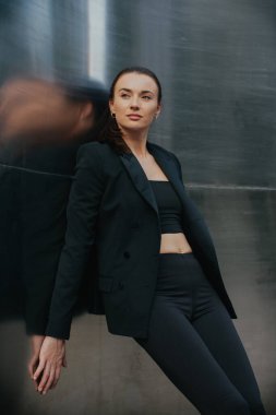 Siyah takım elbiseli güzel bir kızın moda sokak tarzı portresi. Açık havada poz veren güzel esmer.