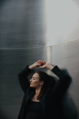 Siyah takım elbiseli güzel bir kızın moda sokak tarzı portresi. Açık havada poz veren güzel esmer.