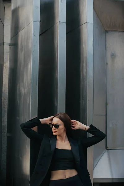 屋外で若いエレガントな女性のファッションの肖像画 黒のスーツサングラスグレーの金属の背景 — ストック写真