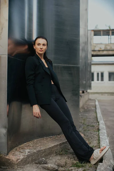 Fashion street style portrait of pretty girl in black suit. Beautiful brunette posing outdoor.