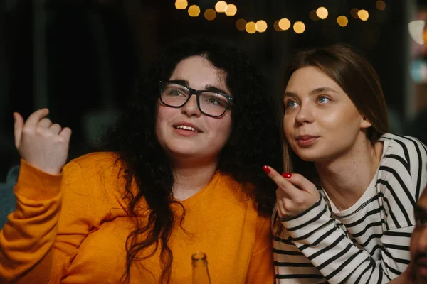 2人の女性の友人は感情的に映画を見ていると豆の袋に座っている間にチップを食べる — ストック写真