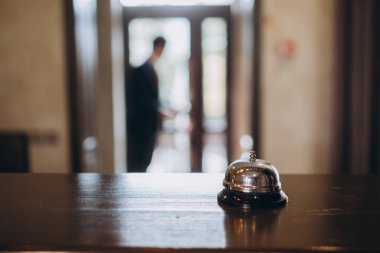 Otele varış. Otel lobisinde çanı olan resepsiyon masası..