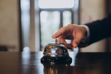 Otele varış. Dikkat çekmek için otel resepsiyon zilini çalan bir adam..