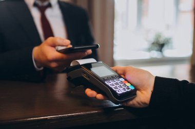 Bir işadamı, NFC teknolojisini kullanarak bir otel odasının faturasını öder..