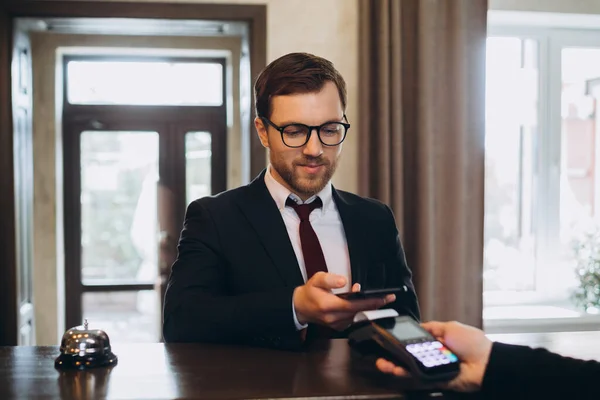 ビジネスマンは Nfc技術を使用してスマートフォンを介してホテルの部屋の請求書を支払う — ストック写真