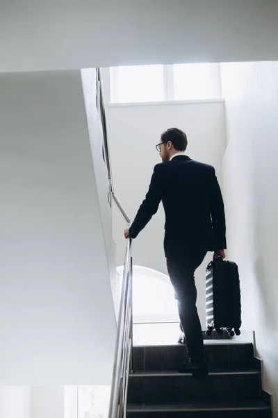 一个带着手提箱的商人正在酒店的楼梯上走着 — 图库照片
