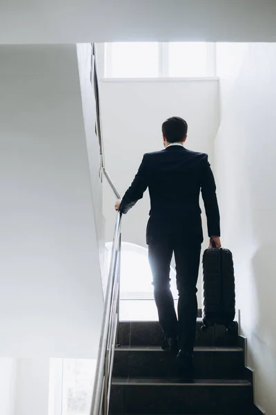 一个带着手提箱的商人正在酒店的楼梯上走着 — 图库照片