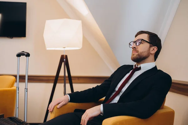 Stock image A businessman is resting while sitting in a comfortable chair in a hotel room.