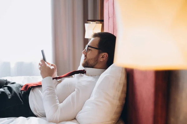 携帯電話を持つホテルの部屋で働く若いビジネスマン — ストック写真