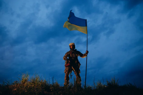 Збройний Український Військовослужбовець Вечірній Час Тримає Національний Прапор — стокове фото