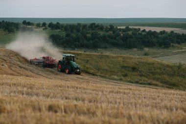 Bir traktör buğday tarlasını sürüyor. Çiftçi işi ve hasat kavramı..