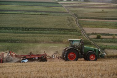 Bir traktör buğday tarlasını sürüyor. Çiftçi işi ve hasat kavramı..