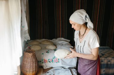 Ukrayna işlemeli elbiseli bir kadın elinde çiğ ekmek tutuyor..