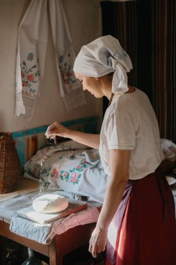 Geleneksel ekmek pişirme süreci. Ulusal Ukrayna elbiseli bir kadın ekmek pişiriyor.