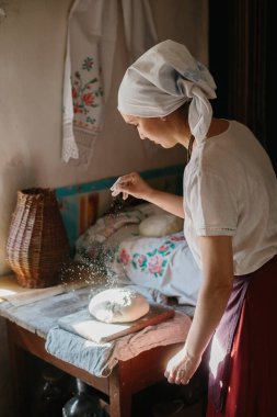 Geleneksel ekmek pişirme süreci. Ulusal Ukrayna elbiseli bir kadın ekmek pişiriyor.