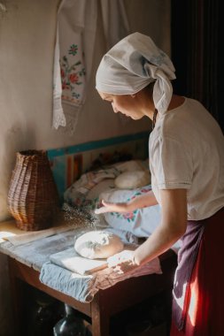 Geleneksel ekmek pişirme süreci. Ulusal Ukrayna elbiseli bir kadın ekmek pişiriyor.