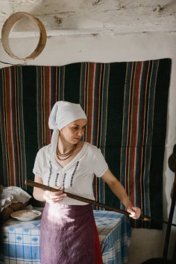 Ukrayna ulusal giysili bir kadın odun sobasının yanında çalışıyor. Geleneksel ekmek pişirme süreci.
