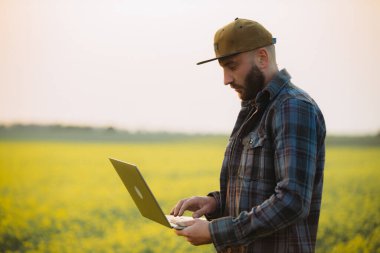 Çiftçi ile alan üstünde laptop.