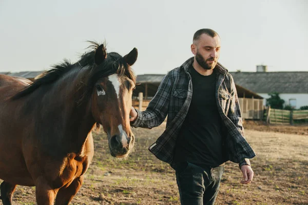 若い農夫が農場で馬と仕事をしている — ストック写真