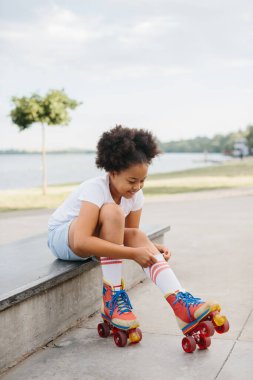 Kumsaldaki bir kaykay parkında kaykay yaparken paten kayan tatlı Afro-Amerikalı genç kız..