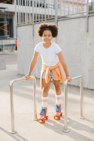 stock image African-American young girl in roller skates having fun outdoors. The girl smiles looking at the camera.