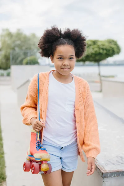 Stock image A young girl came to skate in the skatepark. African American girl holding vintage rollers tied with shoelaces.