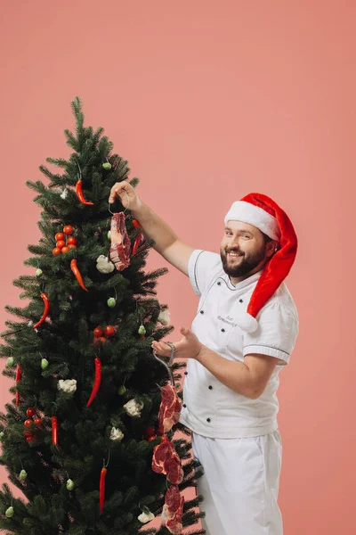 料理とクリスマス休日のコンセプト クリスマスツリーの背景にあるサンタの帽子のシェフ — ストック写真