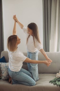 Neşeli anne küçük kızıyla kanepede gülüyor, neşeli genç anne sevimli bebekle eğleniyor..